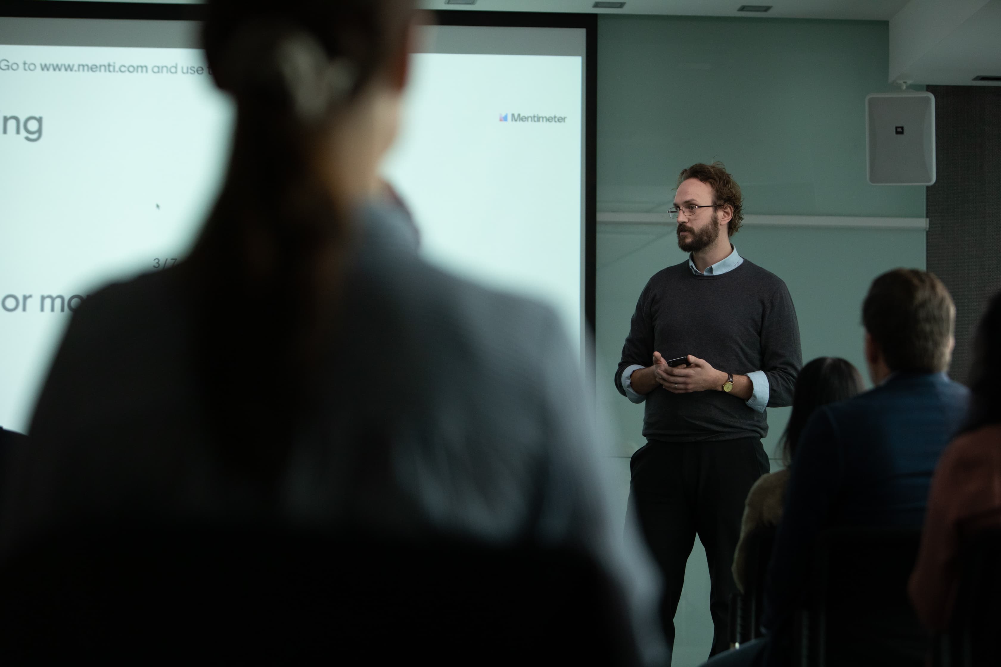 a man stands in front of an audience presenting with Mentimeter