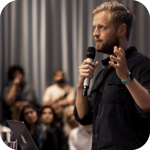 A man speaking in front of an audience with a microphone