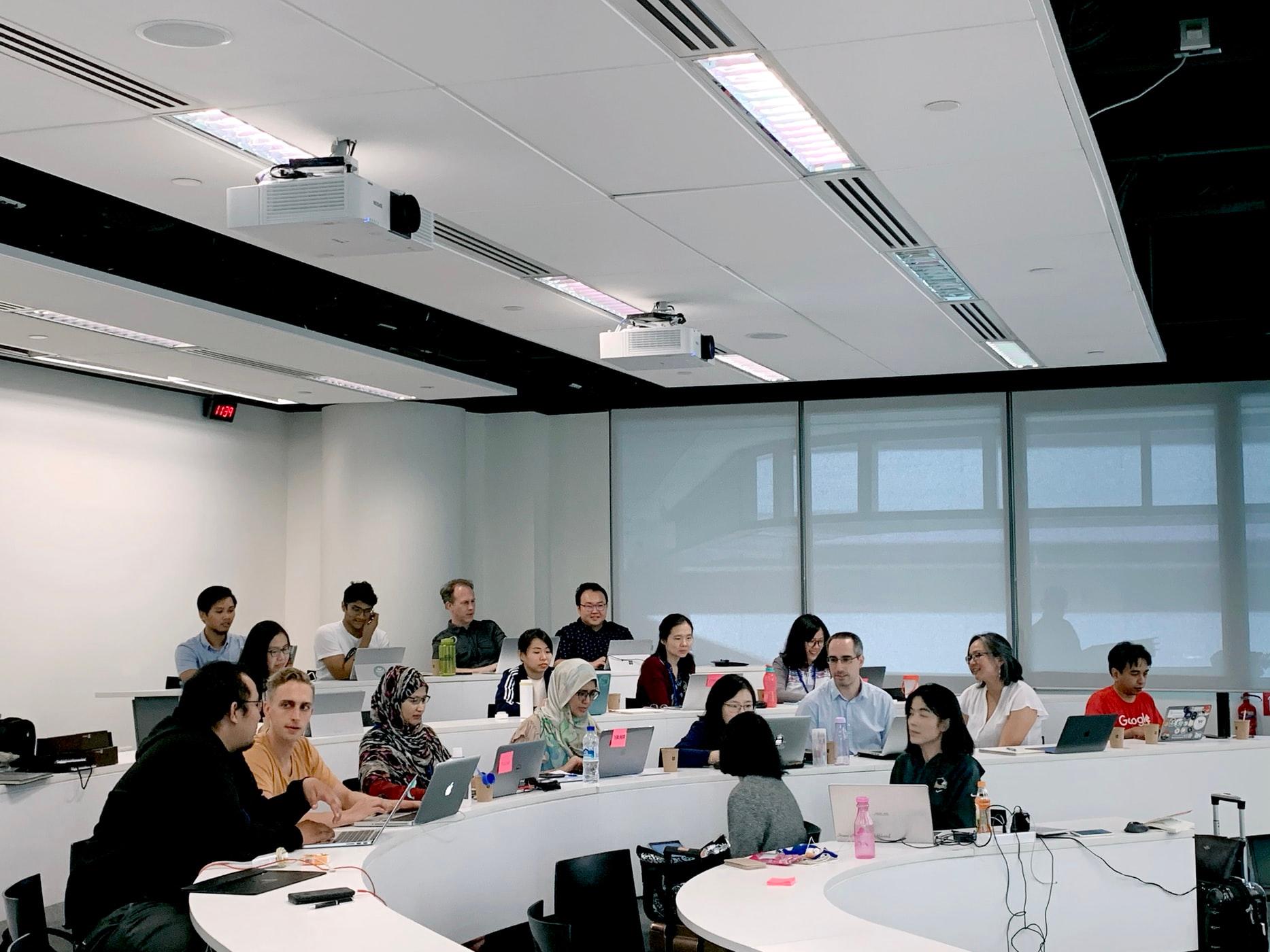 Groups of students in a lecture hall together 